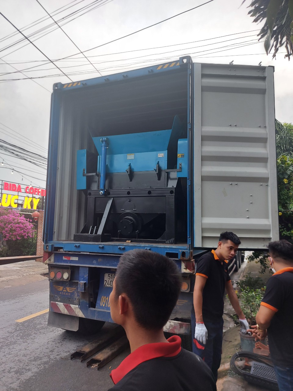 công nhân đang đặt máy băm nhựa phế liệu lên thùng xe tải vận chuyển cho bên mua